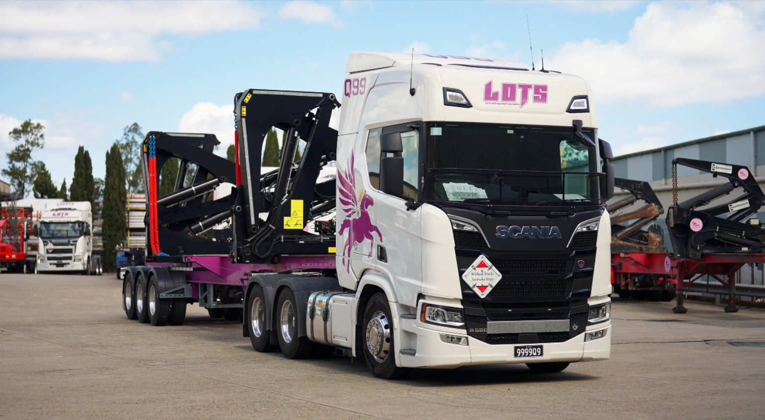 Real white Scania LOTS side-loader truck with purple winged horse branding at the depot